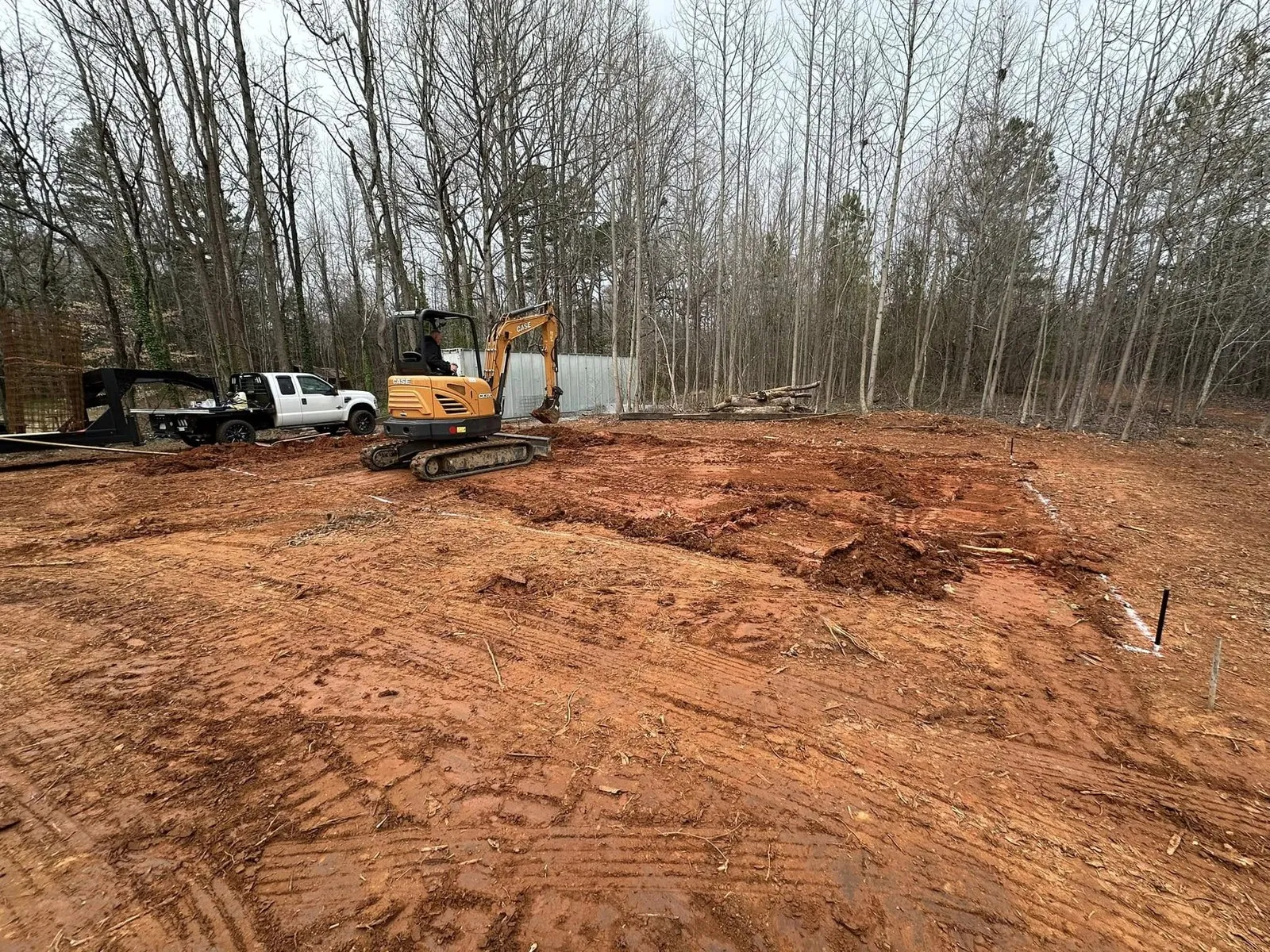 Excavator and grapple truck working a lot cleared of trees