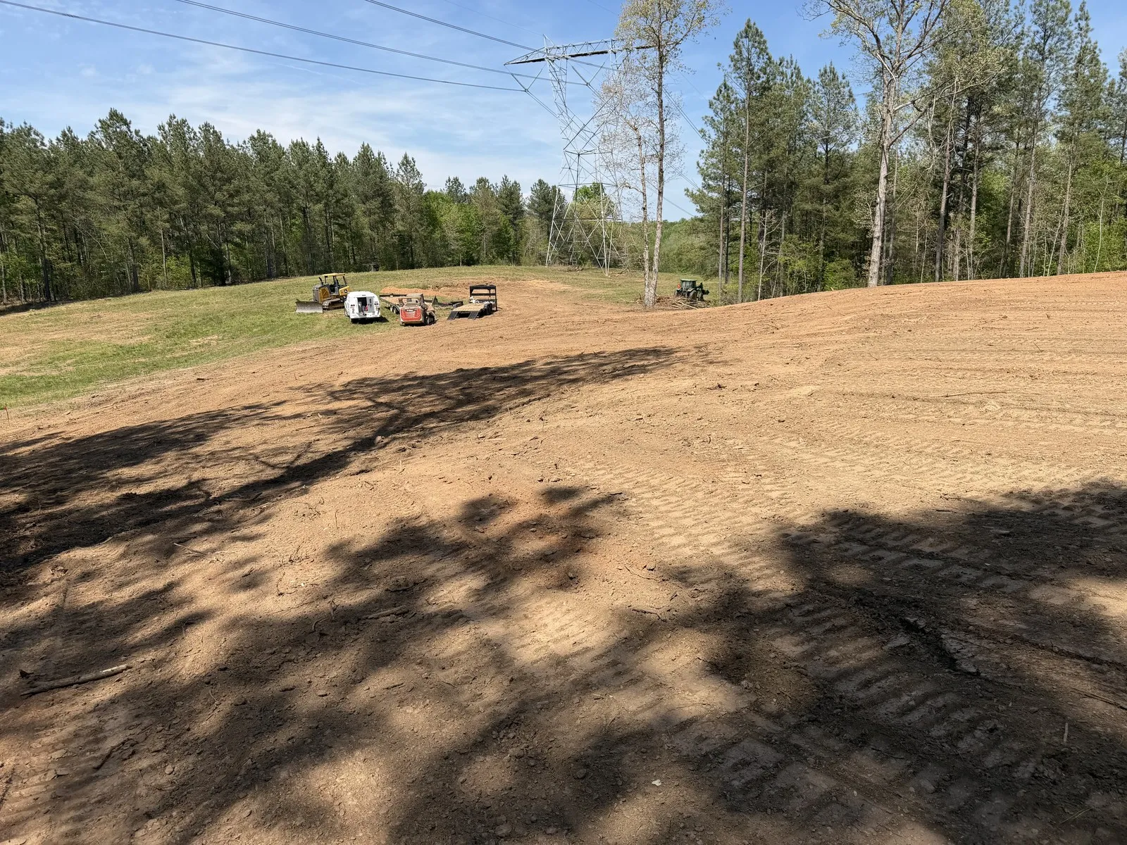 Cleared and graded red clay beside pine woods on a job near Shelby, NC